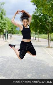 Portrait of young woman in sports doing exercise, jumping, in urban background