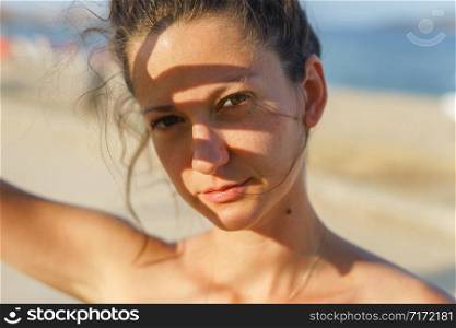 Portrait of young woman in sunny day summer or spring or autumn with shade on her face brunette real person looking to the camera