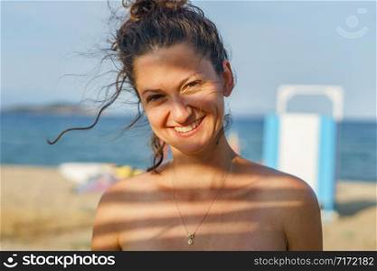 Portrait of young woman in sunny day summer or spring or autumn with shade on her face brunette real person smiling
