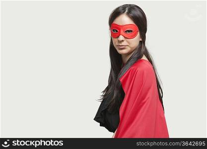 Portrait of young woman in superhero costume against gray background