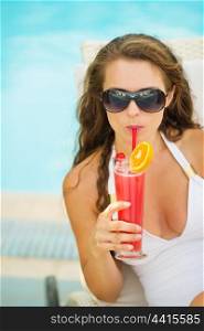 Portrait of young woman in swimsuit drinking cocktail