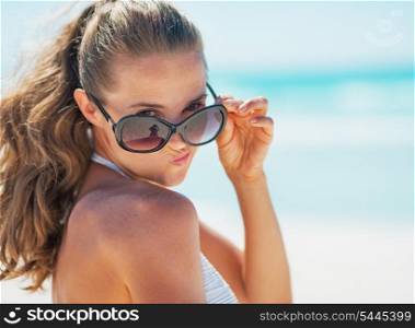 Portrait of young woman in swimsuit on beach making funny face
