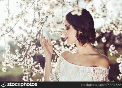 Portrait of young woman in the flowered garden in the spring time. Almond flowers blossoms