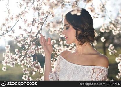 Portrait of young woman in the flowered garden in the spring time. Almond flowers blossoms