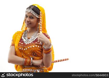 Portrait of young woman in traditional wear holding dandiyas isolated over white background