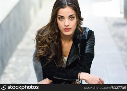 Portrait of young woman in urban background wearing casual clothes looking at camera