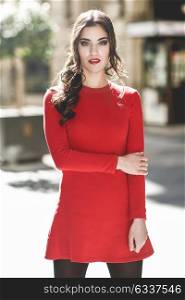 Portrait of young woman in urban background wearing red dress