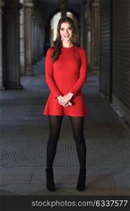 Portrait of young woman in urban background wearing red dress