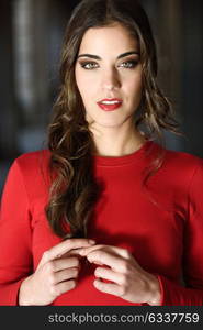 Portrait of young woman in urban background wearing red dress