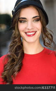 Portrait of young woman in urban background wearing red dress and hat