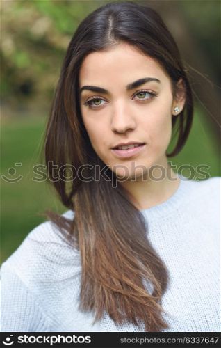 Portrait of young woman in urban park wearing casual clothes. Girl wearing sweater