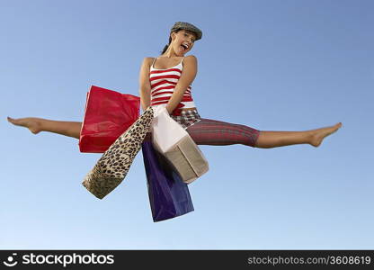 Portrait of young woman jumping with shopping bags