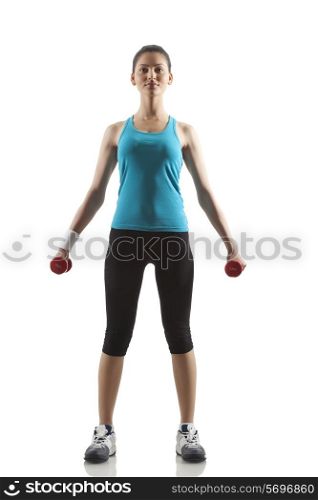 Portrait of young woman lifting dumbbells against white background