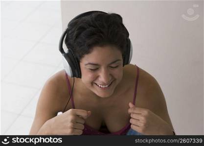 Portrait of young woman listening to music and snapping fingers