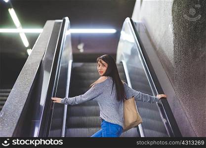 Portrait of young woman looking back from city escalator