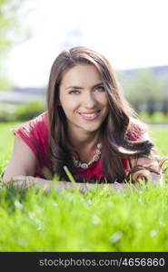 Portrait of young woman lying on a green lawn