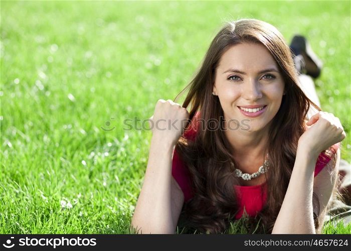 Portrait of young woman lying on a green lawn