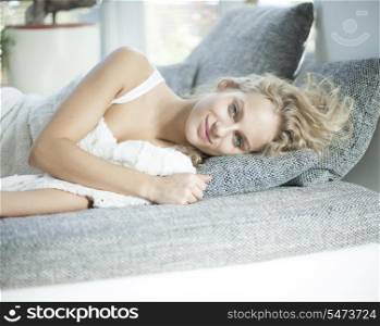 Portrait of young woman lying on sofa at home