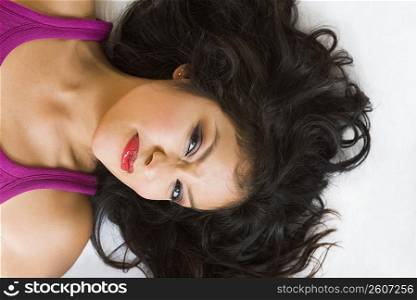 Portrait of young woman lying on white rug