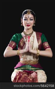 Portrait of young woman making Bharatanatyam gesture called Anjali on black background