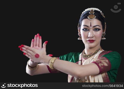 Portrait of young woman making Bharatanatyam gesture called Chakram on black background