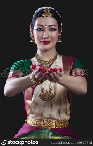 Portrait of young woman making Bharatanatyam gesture called Pushpaputam on black background