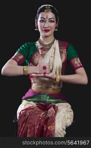 Portrait of young woman making Bharatanatyam gesture called Shivalingam on black background