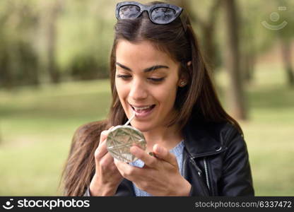 Portrait of young woman making up herself in urban background