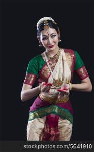 Portrait of young woman performing Indian classical dance over black background