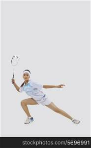 Portrait of young woman playing badminton isolated over gray background