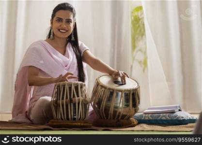 Portrait of young woman playing Tabla at home