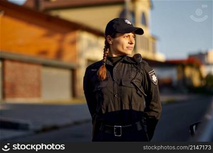 Portrait of young woman police officer with walkie-talkie in uniform outdoors looking side. Woman police officer in uniform outdoors portrait