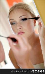 Portrait of young woman putting mascara on