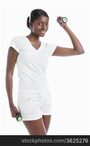 Portrait of young woman raising dumbbell over background