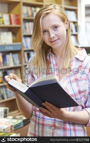 Portrait Of Young Woman Reading Book In Bookstore