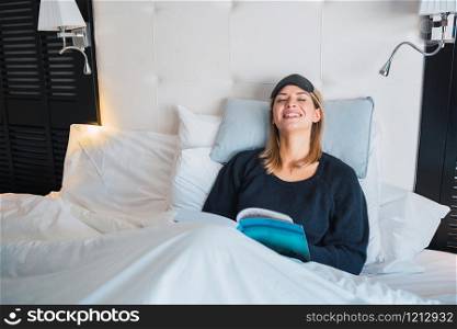 Portrait of young woman relaxed and laying on bed while reading a book. Lifestyle concept.