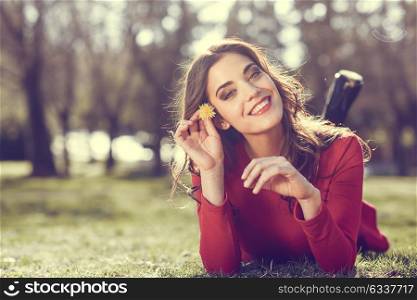 Portrait of young woman rest in the park with a dandelion in her hair, lying on the grass