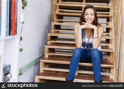 Portrait of young woman sitting at the stairs in office. Portrait of young woman wearing casual clothes sitting at the stairs in office