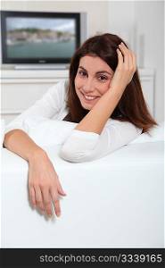 Portrait of young woman sitting in sofa watching television