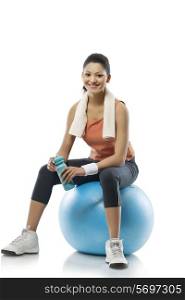 Portrait of young woman sitting on a fitness ball after workout over white background