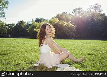 Portrait of young woman sitting on park grass