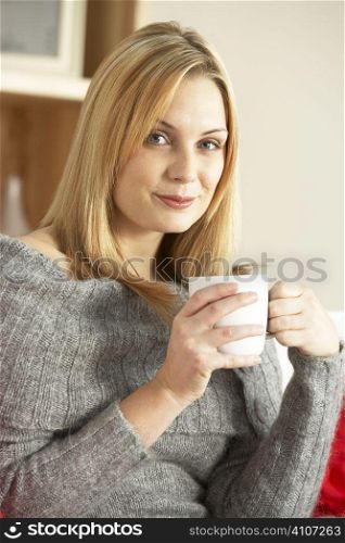 Portrait Of Young Woman Sitting On Sofa With Cup Of Coffee