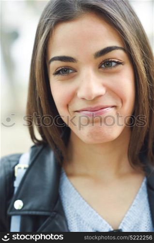 Portrait of young woman smiling in urban background wearing casual clothes.