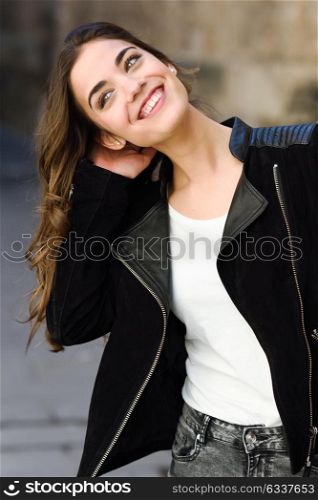 Portrait of young woman smiling in urban background wearing casual clothes