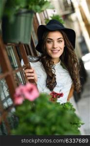 Portrait of young woman smiling in urban background wearing casual clothes and hat