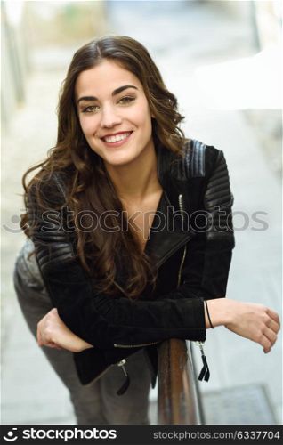 Portrait of young woman smiling in urban background wearing casual clothes with long curly hair