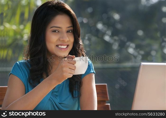 Portrait of young woman smiling while having coffee