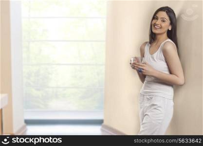 Portrait of young woman smiling while holding cup of herbal tea