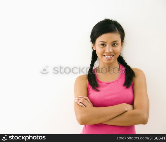 Portrait of young woman standing with arms crossed smiling.