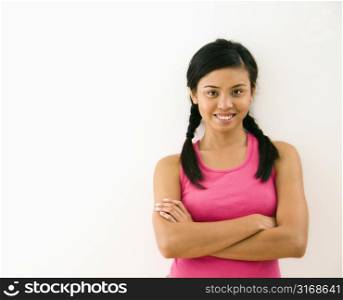 Portrait of young woman standing with arms crossed smiling.